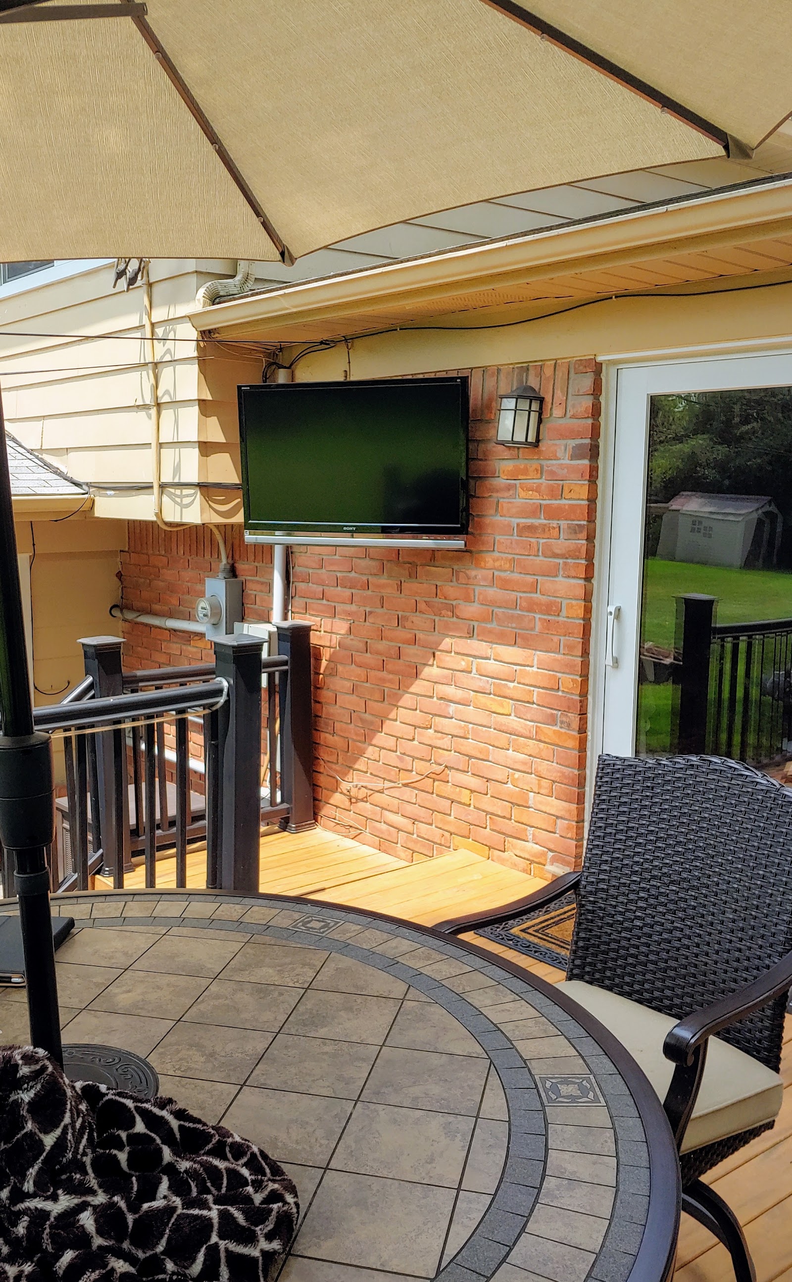 Weatherproof TV mounted on a covered patio for outdoor backyard entertainment