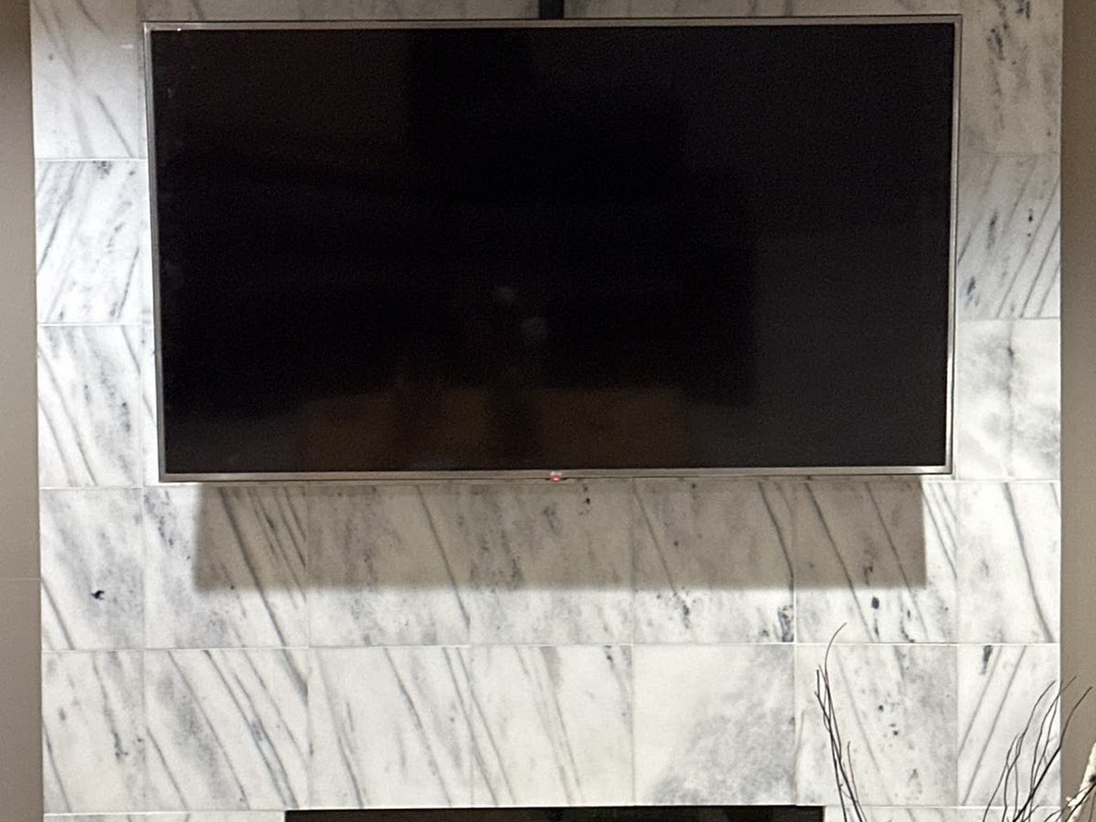 Flat-screen TV professionally mounted above a marble fireplace in a Metro Detroit home