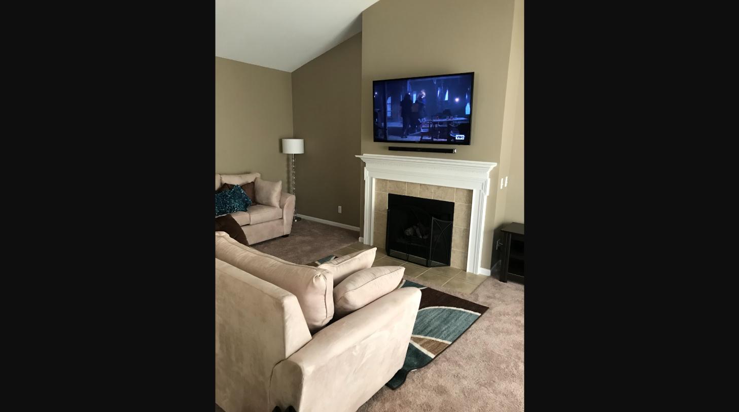 Flat-screen TV professionally mounted above a fireplace with wires concealed in a Metro Detroit living room